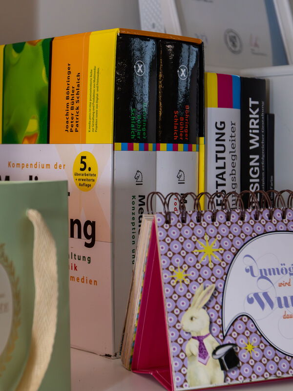 Bücherregal mit Büchern, einem Kalender und einer Geschenktüte