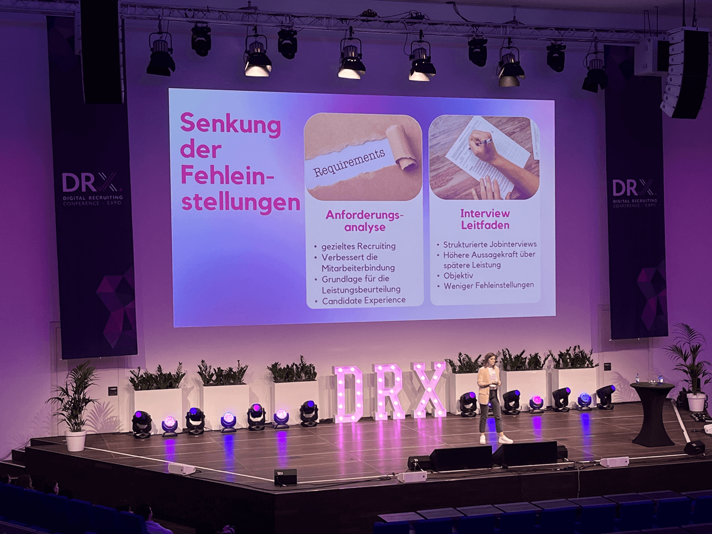 Bühne mit einer Präsentation über die Senkung von Fehlbesetzungen, mit den Titeln 'Anforderungsanalyse'